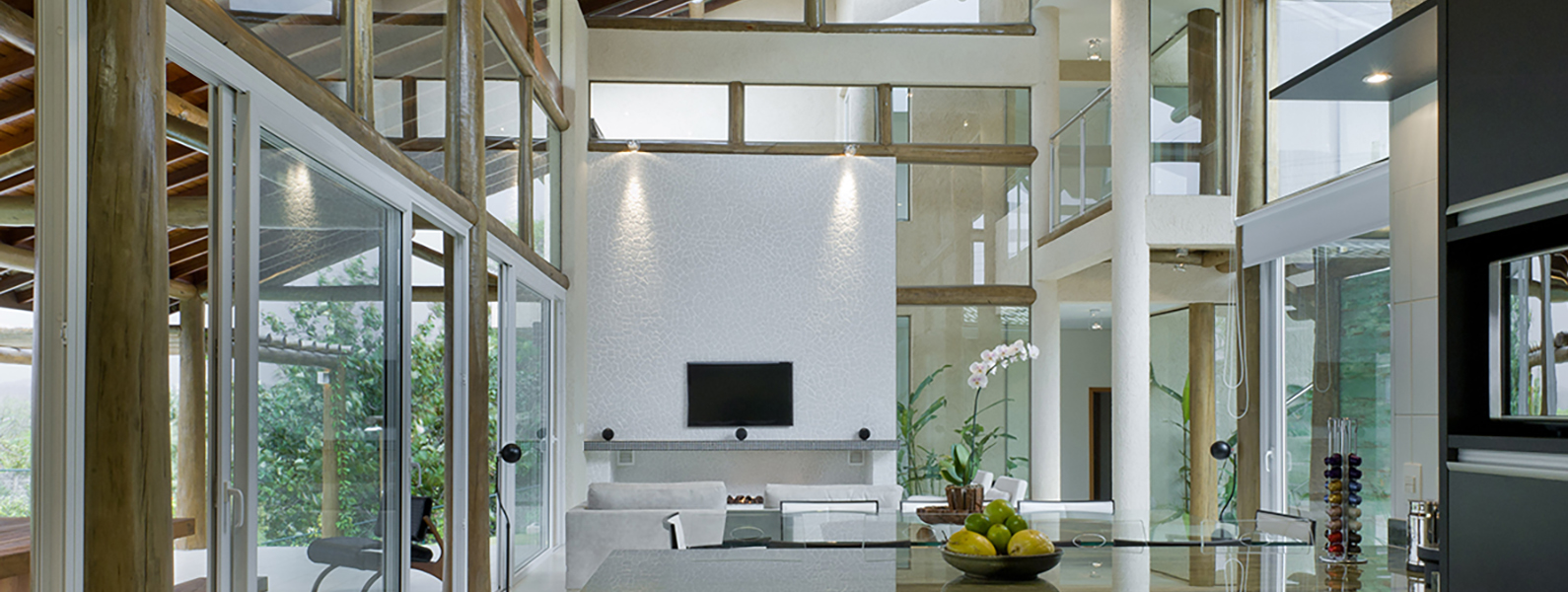 Vista interior de una casa con salón y cocina con paredes formadas por ventanas de pvc corredizas de cristal