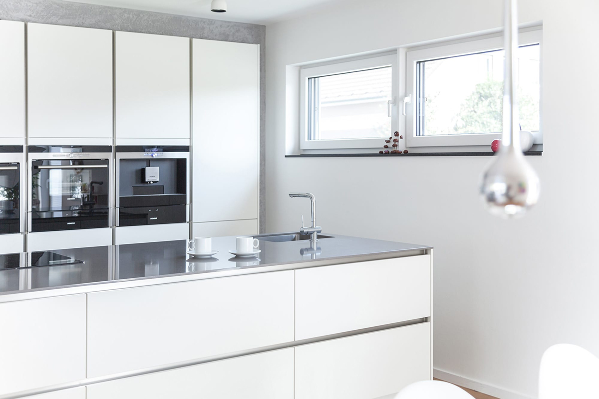 Cocina blanca con isla central y sistema de ventanas Kömmerling