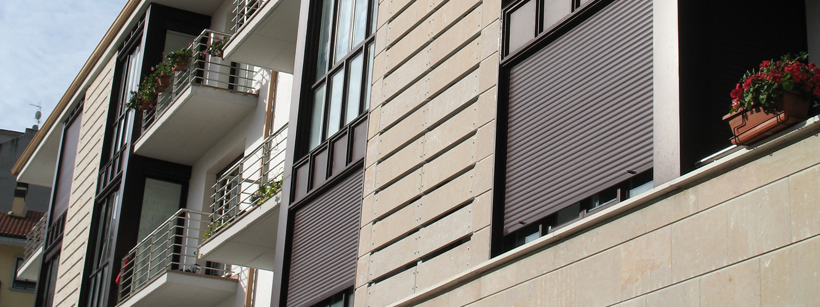 Fachada de edificio marrón claro con ventanas de pvc marrón oscuro y sistema de persianas Kömmerling RolaPlus