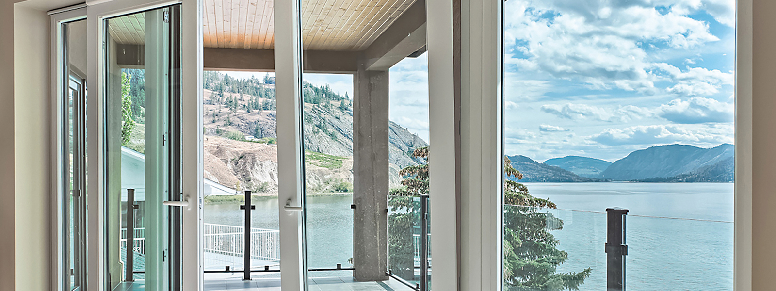 Ventana corredera con perfil blanco con un lago y montañas de fondo